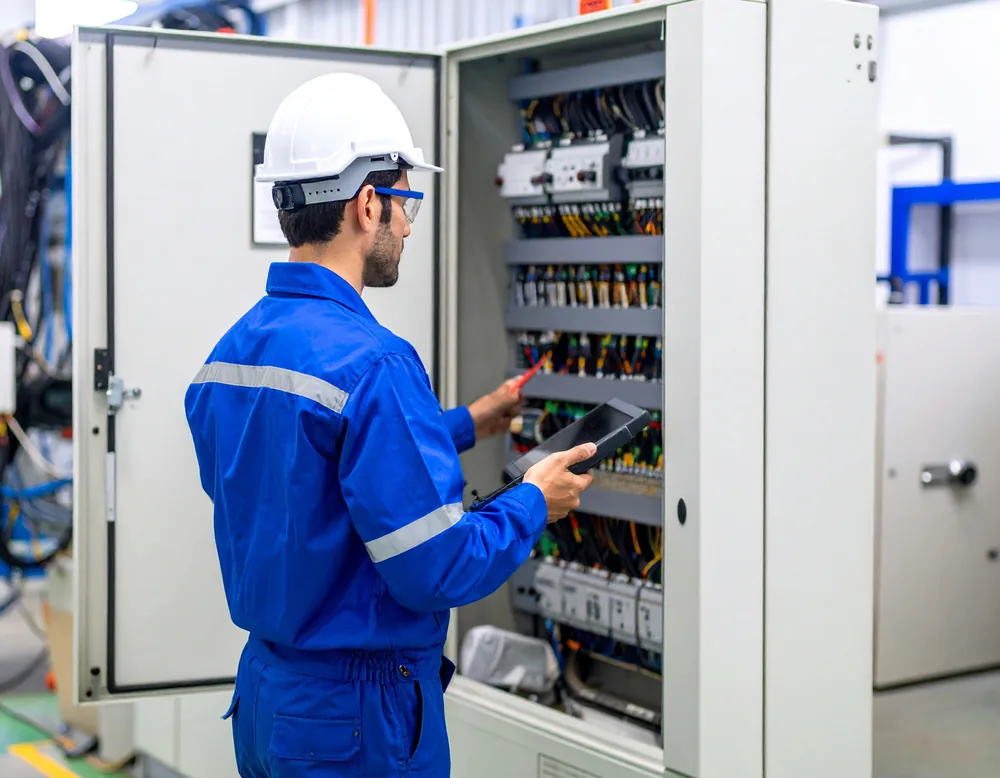 Electrical technician inspecting industrial control equipment